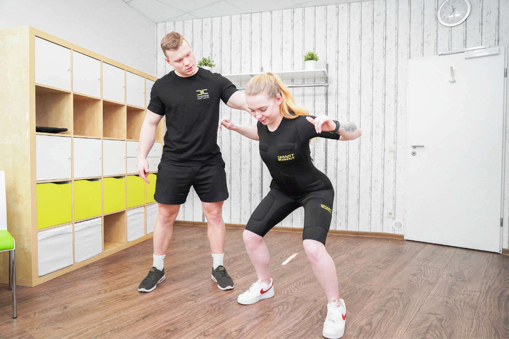 Frau macht Kniebeuge beim EMS-Training im Thomas Sport Center Dresden.